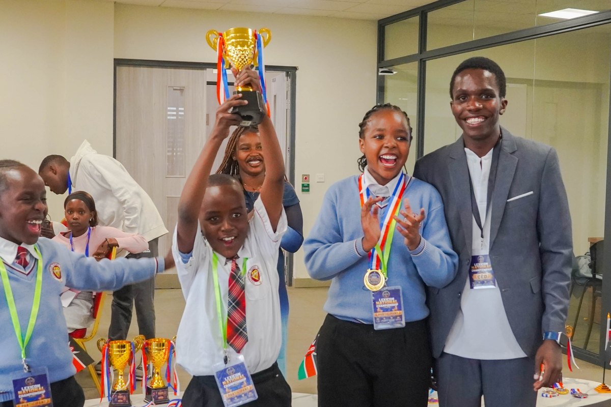 Students and an organiser celebrating a raised trophy